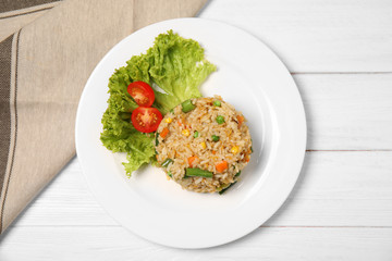 Plate with tasty boiled rice and vegetables on table, top view