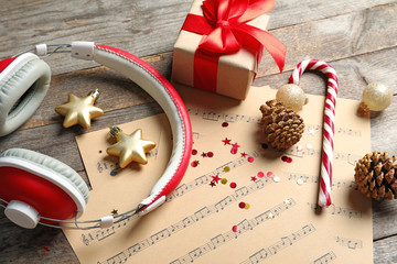Composition with Christmas decorations, music sheets and headphones on wooden background