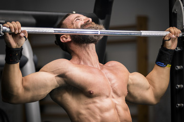Hombre fuerte con grandes m&uacute;sculos haciendo dominadas en el gimnasio. Ponerse en forma.