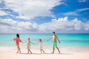 Family of four walking on white beach