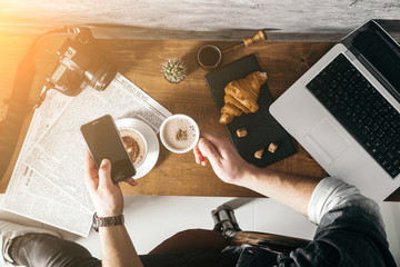 Young man in morning cafe drink coffee and read daily news