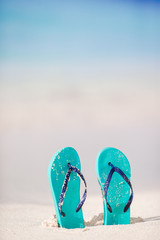Summer mint flip flops with sunglasses on white beach