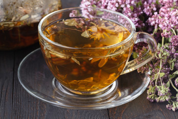 cup of tea with oregano herb on wooden table