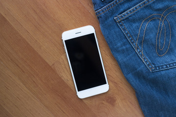Smart phone and jeans on wooden floor