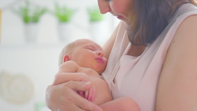 Mother and her newborn baby. Happy mom kissing and hugging her baby. Maternity concept. Motherhood. Happy family. Adoption. Slow motion 4K UHD video 3840x2160