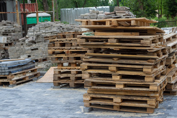 Used wooden euro pallets are stacked at the construction site. In the background are building materials.