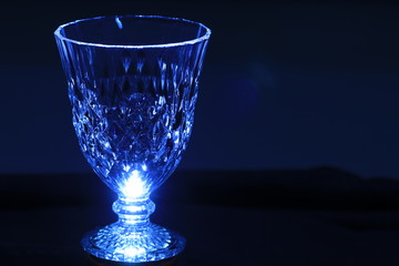 Close up  crystal glass  in blue light on blue background