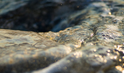 pebble stones on the sea beach, the rolling waves of the sea with foam