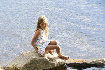 Fototapeta na wymiar Child girl having fun on rock on the beach in summer 