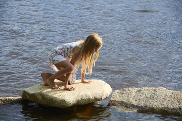  Child girl having fun on rock on the beach in summer
