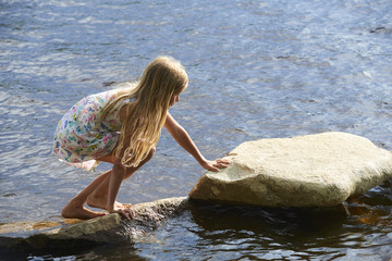  Child girl having fun on rock on the beach in summer
