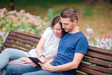 Couple using tablet and cellphone in public park.