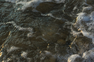 pebble stones on the sea beach, the rolling waves of the sea with foam