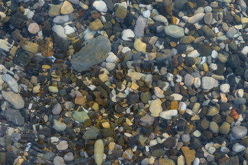 pebble stones on the sea beach, the rolling waves of the sea with foam