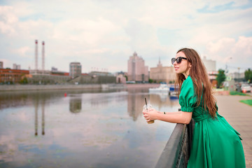 Young woman is looking at the sunset over a river in the city