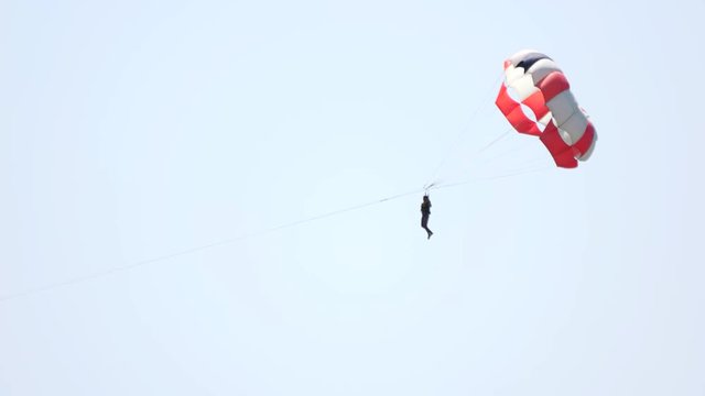 Man with parachute over the sky background. Activities at sea.