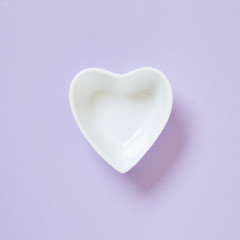 Heart shaped white dish isolated on purple background