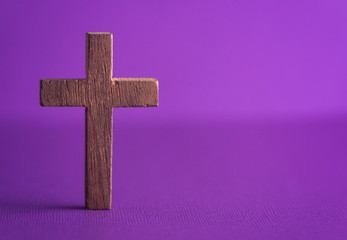 A Simple Wooden Cross on a Purple Background