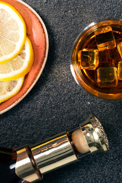Cognac with lemon wedges on brown plate. On a wooden background.Vertical picture.