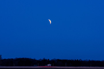 A lunar eclipse hangs over a country farm house
