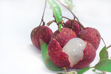 Close up of fresh lychee and peeled showing the red skin and white flesh with green leaf