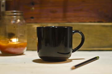 A blank black coffee mug on the old shop work bench in the morning light. 