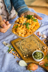 Woman holds and tastes Indian chickpea salad with grated carrot, onion, garlic paste, tahini sesame seeds paste and fresh green herbs. Vegan, vegetarian healthy food.