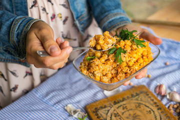 Woman holds and tastes Indian chickpea salad with grated carrot, onion, garlic paste, tahini sesame seeds paste and fresh green herbs. Vegan, vegetarian healthy food.