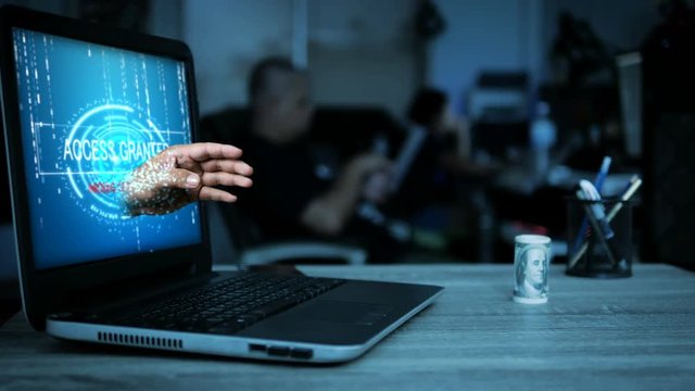 Hacker hand moving from laptop computer monitor to stealing the money on the table with dark tone and grain processed for cyber network security concept