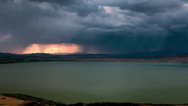 Dark storm clouds rolling over the landscape during colorful sunset as it blocks out the sky over Utah Lake.