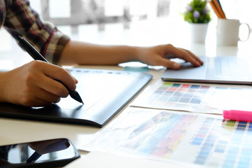 Cropped shot of artist or graphic designer working on digital tablet in studio office.