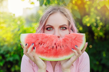 Beautiful young woman with pink hair enjoying watermelon