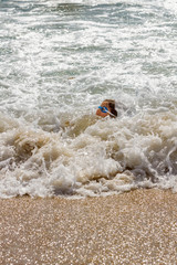 Young Girl Barely Keeping Her Head Above Water In the Foamy Ocean Surf On The Beach