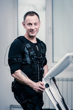 Portrait of athletic man in EMS suit near electro muscle stimulation machine