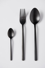 elevated view of black spoons and fork on white background, minimalistic concept