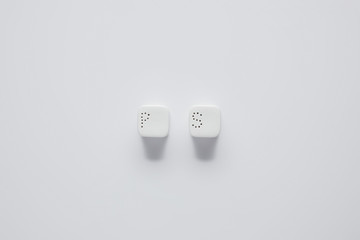 top view of pepper caster and saltcellar on white table, minimalistic concept