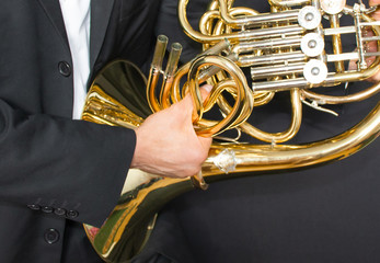 French horn player. Music instrument horn in the hands of hornist. A man in a suit  with a musical instrument.  - obrazy, fototapety, plakaty