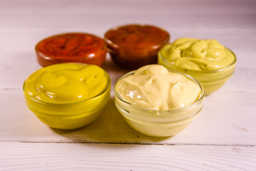 Different sauces in glass bowls on wooden table