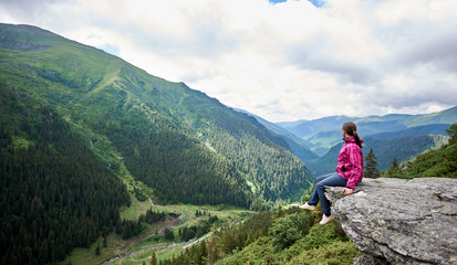 Fototapeta na wymiar Shot of a woman sitting on the edge of a rock in the mountains resting after hiking copyspace landcape view scenery harmony recreation happiness active living environment ecology.