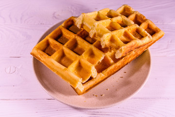 Ceramic plate with belgian waffles on wooden table