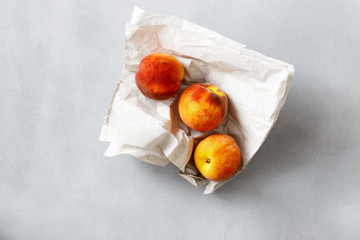 Three ripe peaches gray concrete background top view