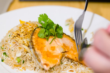 fried sliced salmon with fried rice.man hands use fork and spoon for fusion food.sliced salmon with...