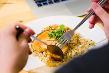 fried sliced salmon with fried rice.man hands use fork and spoon for fusion food.sliced salmon with...