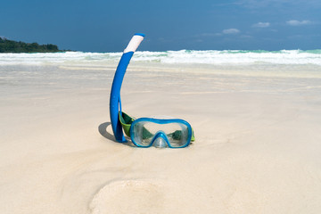 black diving mask and snorkel on the beach sand