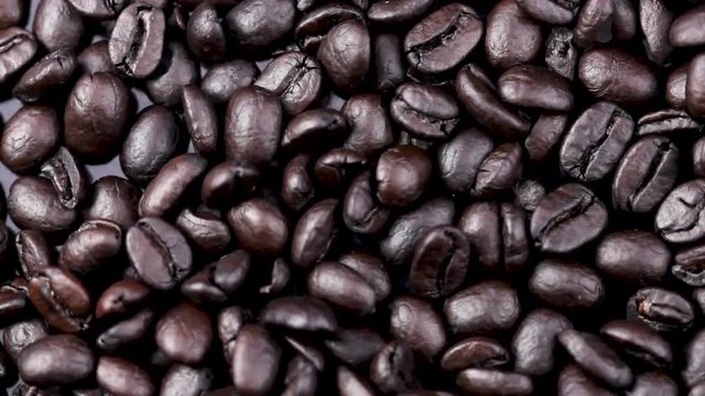 Black coffee beans pattern rotating. Close up macro.