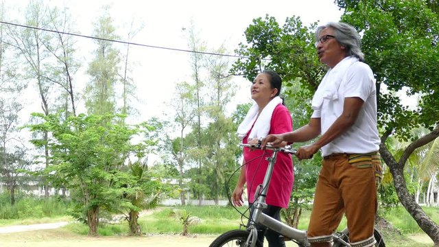 Senior asian couple walking together after finised exercise in park
