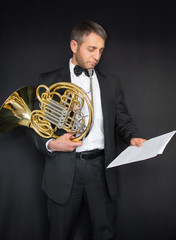 French horn. Handle of a musical instrument in the hands of a rogant. Man in suit and butterfly with musical instrument. He holds musical notes in his hand.