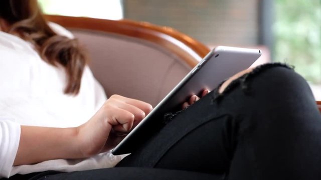 A woman holding , using and pointing at tablet pc screen in modern cafe