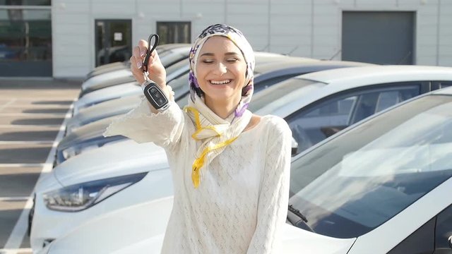 Concept of buying a car. Happy muslim woman holding car key.