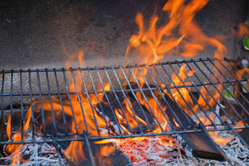 leerer Grillrost mit Flammen und brennenden Holzscheiten